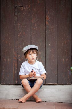 Cute little child, boy, holding big metal key and a book, willin