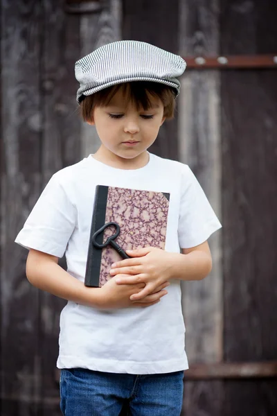 Cute little child, boy, holding big metal key and a book, willin — Stockfoto