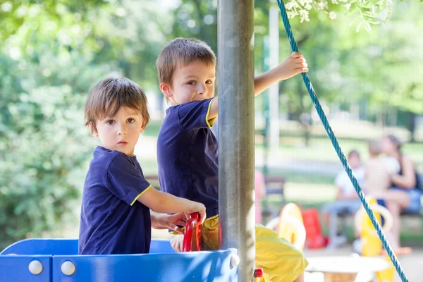 Due dolci ragazzi, fratelli, che giocano in una barca nel parco giochi — Foto Stock