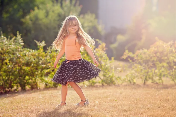 Cute little girl with skirt, dancing and swirling around, summer — Stock Photo, Image