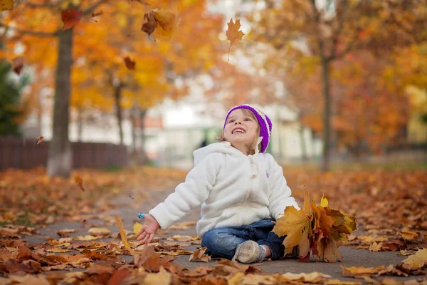Adorable little girl in the park, playing with leaves — Stok fotoğraf