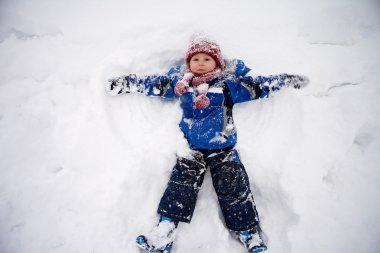 Sevimli küçük çocuk yatan mavi ceket, kırmızı şapka ve atkı,