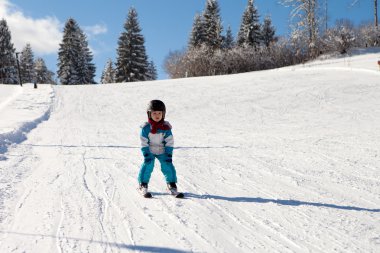 Mavi ceket ve bir kask ile sevimli küçük çocuk Kayak
