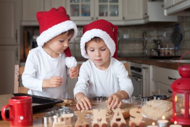 Noel Baba şapkası ile iki yakışıklı çocuk mutfakta kurabiye hazırlama
