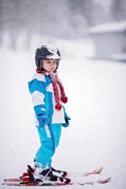 Mavi ceket ve bir kask ile sevimli küçük çocuk Kayak