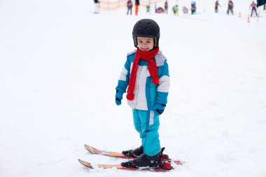 Mavi ceket ve bir kask ile sevimli küçük çocuk Kayak