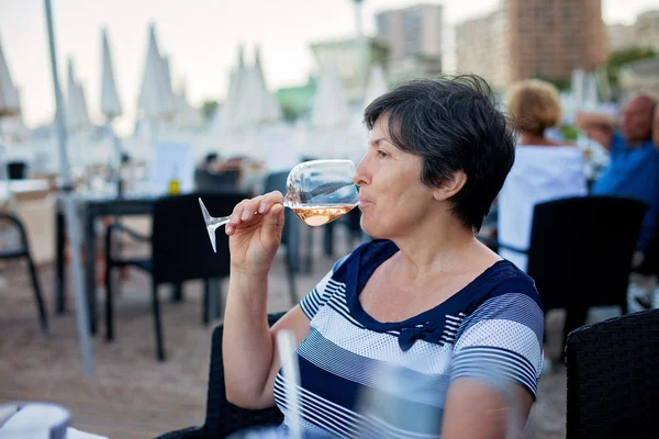 Middelbare leeftijd vrouw, drinken Rose wijn in een strandrestaurant — Stockfoto