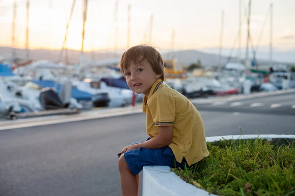 Doce criança, menino, sentado e observando o porto — Fotografia de Stock