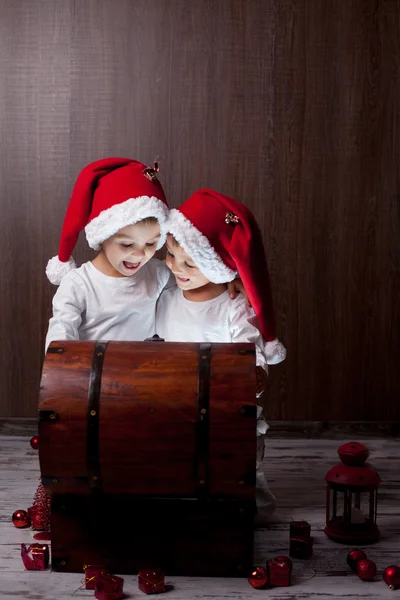 Deux adorables garçons, ouvrant la poitrine en bois, la lumière brillante de insi — Photo