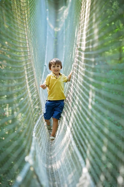 Criança bonito, menino, andando em uma estrutura de playground corda , — Fotografia de Stock