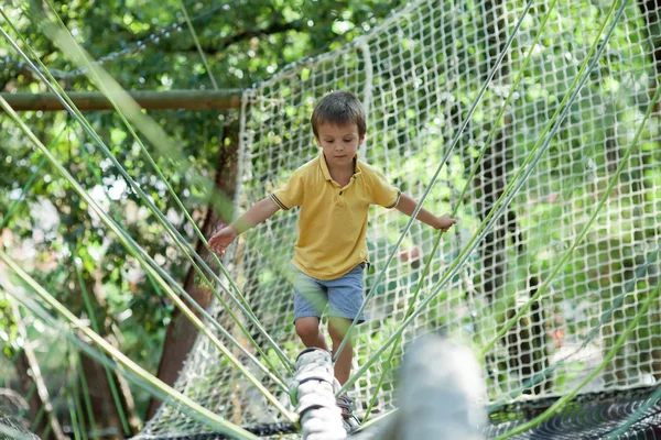 Lindo niño escalando en una estructura de patio de cuerda — Foto de Stock
