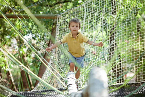 Lindo niño escalando en una estructura de patio de cuerda —  Fotos de Stock