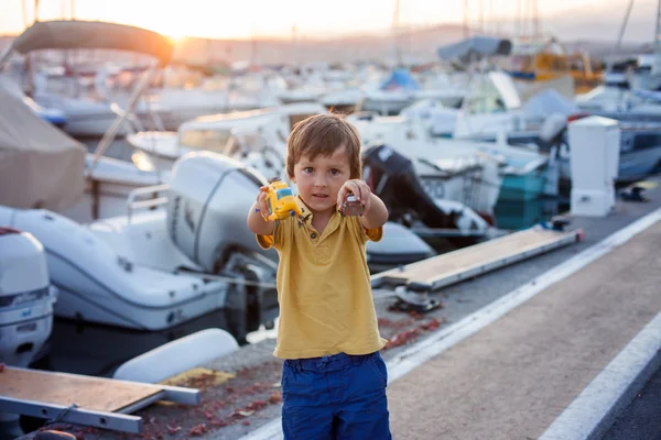 Счастливый милый маленький ребенок, мальчик, играющий с вертолетом в порту — стоковое фото