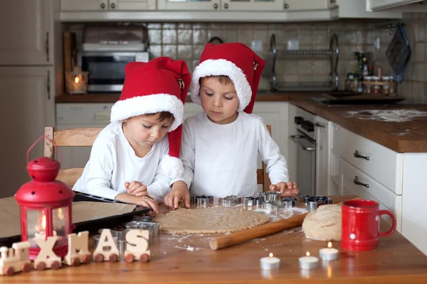 Dwa cute chłopców z santa hat, przygotowanie ciasteczek w kuchni — Zdjęcie stockowe