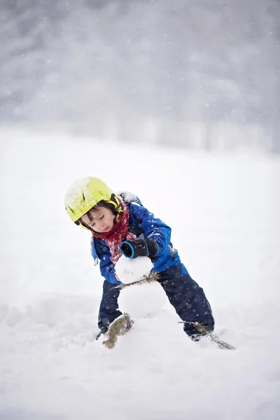 Счастливый мальчик, играющий в снегу — стоковое фото