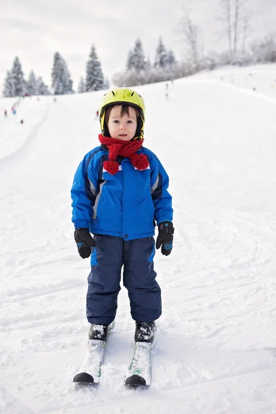 Adorabile bambino con giacca blu e casco, sci — Foto Stock