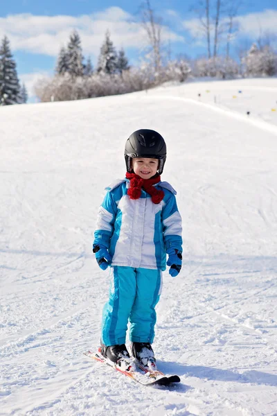 Adorable little boy with blue jacket and a helmet, skiing — Stock Photo, Image