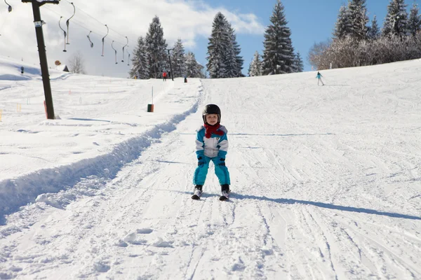 Bedårande liten pojke med blå jacka och hjälm, skidåkning — Stockfoto