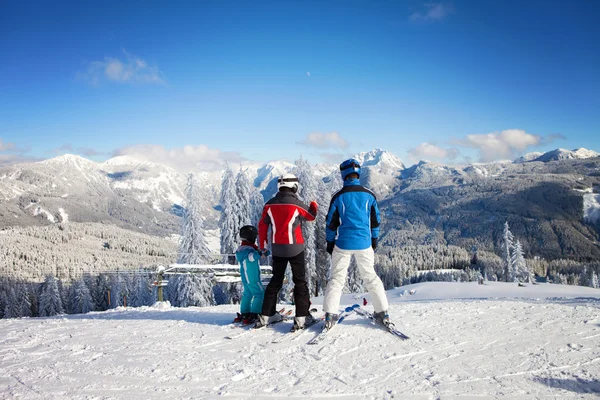 Gelukkige familie in winter kleding in het skiresort — Stockfoto