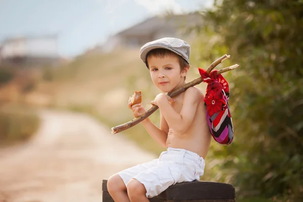 Lindo niño pequeño, sentado en una maleta grande y vieja, vintage, sosteniendo — Foto de Stock