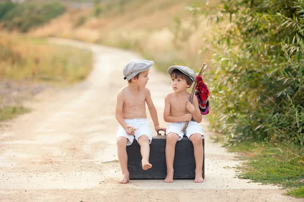 Two boys, sitting on a big old vintage suitcase, playing with to — Stock Photo, Image