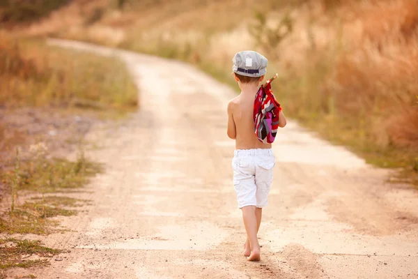 Niedlichen kleinen Jungen, die ein Bündel in der Hand halten, Brot essen und lächeln, wa — Stockfoto