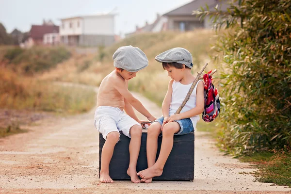 Due ragazzi, seduti su una grande vecchia valigia vintage, a giocare con la mamma — Foto Stock