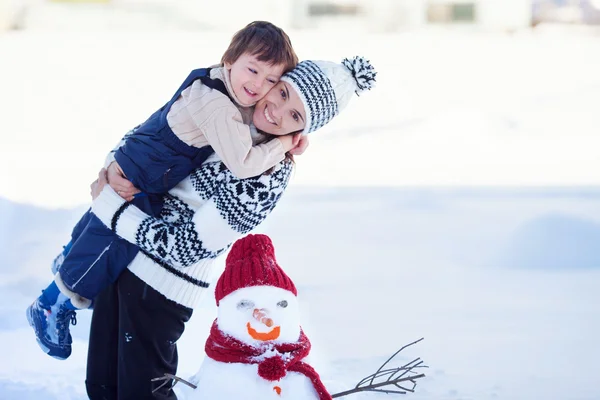 Gelukkig prachtige familie gebouw sneeuwpop in de tuin, winter, — Stockfoto