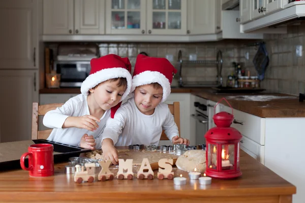 Dos chicos lindos con sombrero de santa, preparando galletas en la cocina —  Fotos de Stock