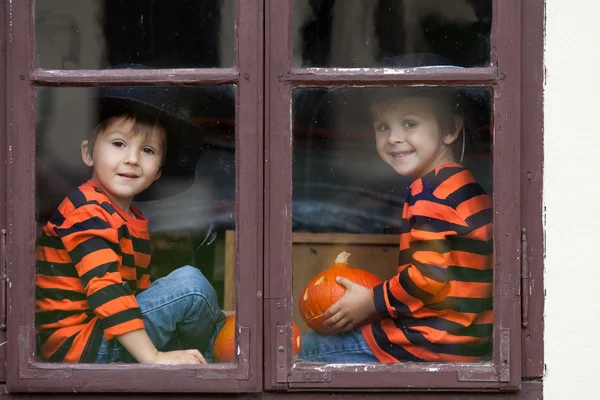 Jack-o-lantern ile bir pencere üzerinde oturan iki yakışıklı çocuk — Stok fotoğraf