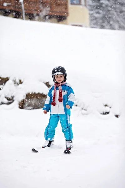 Чарівний маленький хлопчик з блакитною курткою і шоломом, катання на лижах — стокове фото