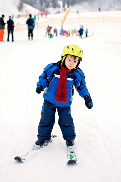 Adorable little boy with blue jacket and a helmet, skiing — Stock Photo, Image