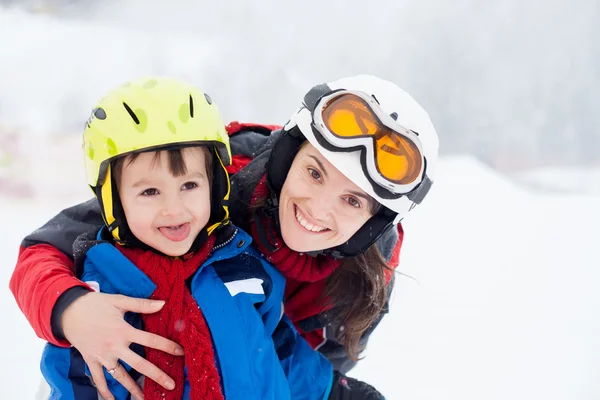 Bela jovem mãe e seu menino, esquiando nas montanhas — Fotografia de Stock