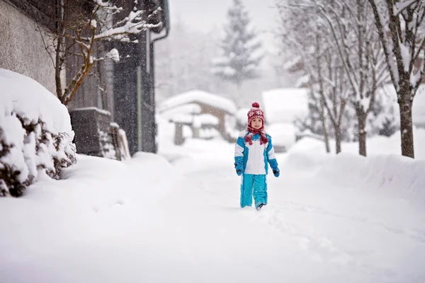 Маленький мальчик в снежном костюме, идущий по снежной тропинке с глубокой — стоковое фото