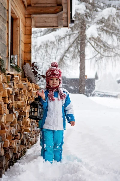 Adorable little boy with lantern, standing in front of a winter — Stock Photo, Image