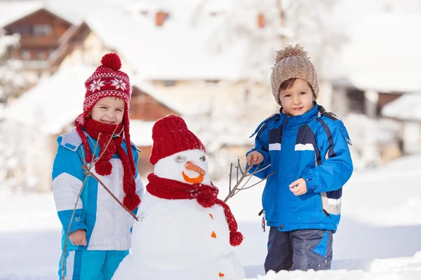 Szczęśliwy piękne dzieci, bracia, budowa snowman w ogrodzie, — Zdjęcie stockowe