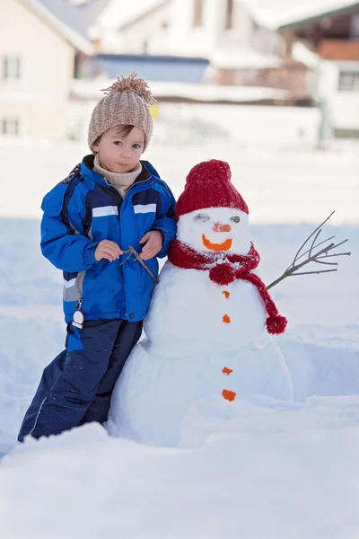 Ευτυχισμένος όμορφο παιδί κτίριο χιονάνθρωπος χειμώνα κήπων, — Φωτογραφία Αρχείου