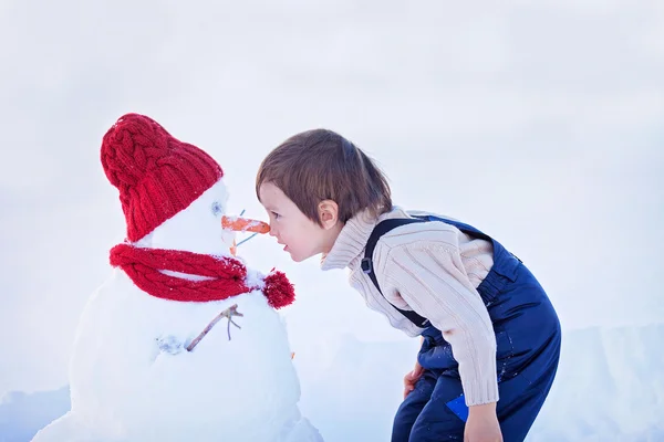 幸せな美しい子鼻 t、冬の庭で雪だるまを構築 — ストック写真