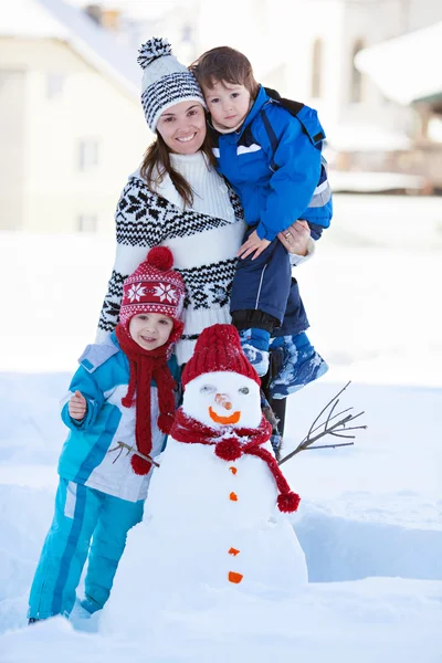 Feliz hermosa familia edificio muñeco de nieve en el jardín, tiempo de invierno , — Foto de Stock