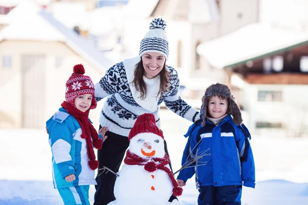 Bonito boneco de neve edifício família feliz no jardim, tempo de inverno , — Fotografia de Stock