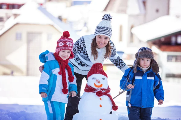 Bonito boneco de neve edifício família feliz no jardim, tempo de inverno , — Fotografia de Stock