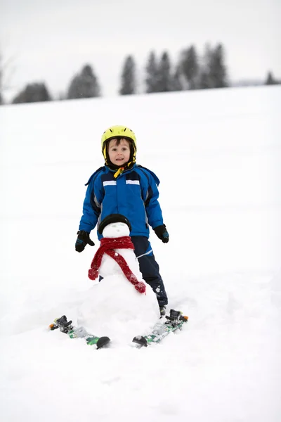 Happy little boy playing in the snow while snowing, helmet Stock Picture