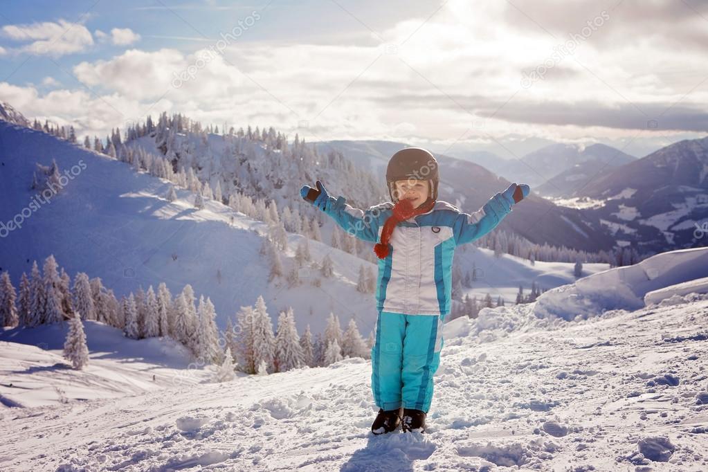 Adorable little boy with blue jacket and a helmet, skiing 