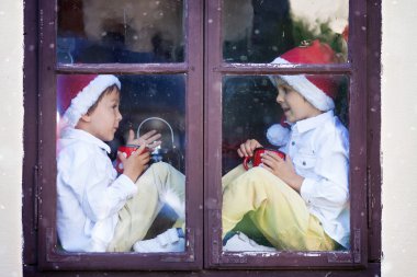 Noel Baba'yı bekleyen bir pencereden bakarak iki yakışıklı çocuk,