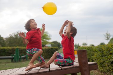 İki erkek, kardeşler, parkta sarı balon ile oynarken