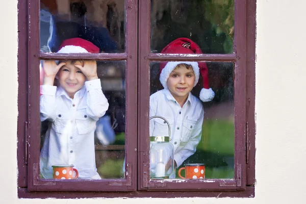 Dois meninos bonitos, olhando através de uma janela, esperando por Papai Noel — Fotografia de Stock