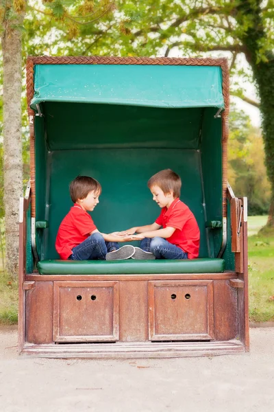 Dos niños, sentados en un banco protegido, jugando a la mano aplaudiendo ga —  Fotos de Stock