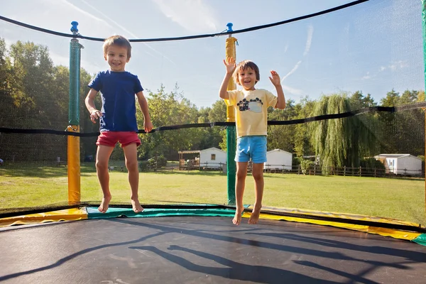 Dois meninos doces, irmãos, pulando em um trampolim, horário de verão, h — Fotografia de Stock