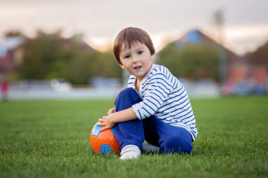 Little toddler boy playing soccer and football, having fun outdo