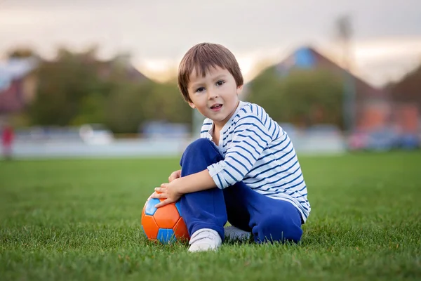 Маленький хлопчик грає у футбол і футбол, розважається на відкритому повітрі — стокове фото